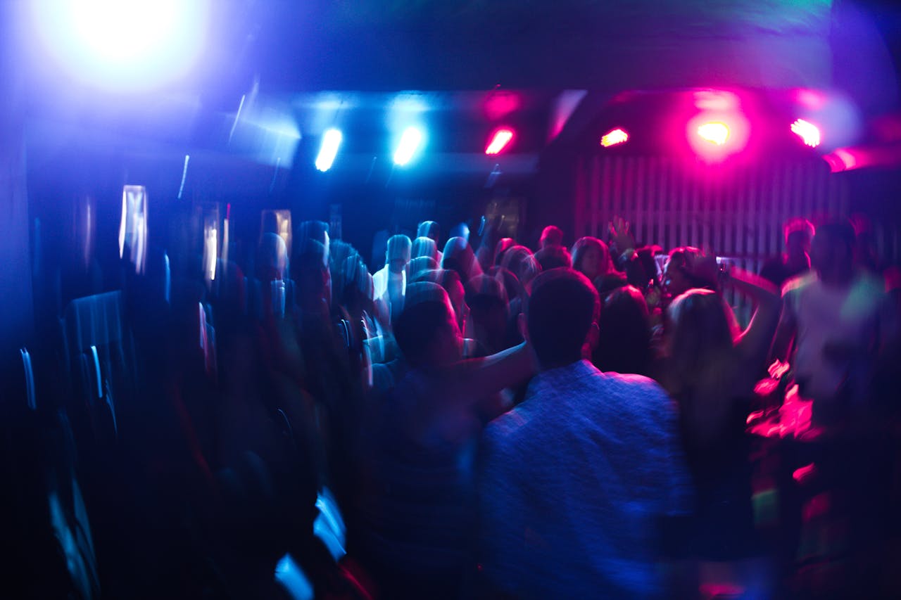 Services Vibrant nightclub scene with blurred dancing crowd and colorful lights.